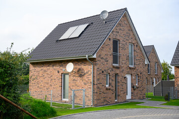 new built house with brick facade in red and solar system on the roof