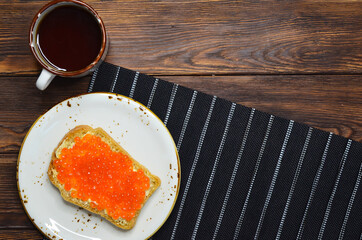 Cup of coffee and sandwich bread with butter and red salmon caviar top view, healthy breakfast