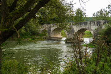 Fototapeta na wymiar Blick auf die Historische Steinbrücke über die Altmühl bei Pfünz vom Ufer aus zwischen den Bäumen