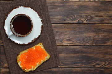 Cup of coffee and sandwich bread with butter and red salmon caviar top view, healthy breakfast