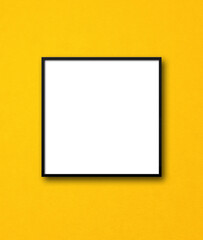 Black square picture frame hanging on a yellow wall