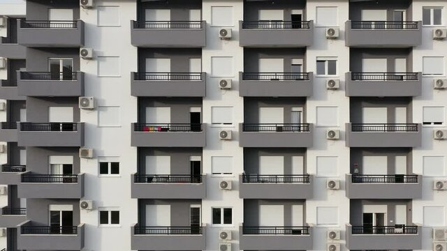 Exterior of a high-rise multi-story apartment building - facade, windows and balconies. Establishing shot aerial footage of a subsidized public housing project.