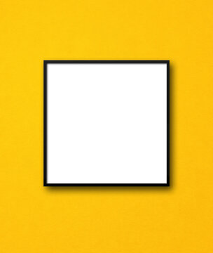 Black square picture frame hanging on a yellow wall