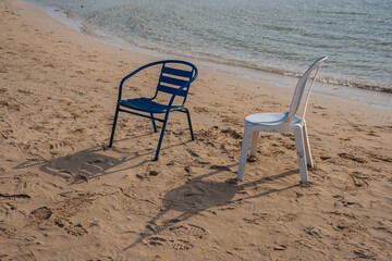 Fototapeta na wymiar Chairs on the sandy seashore with shadows