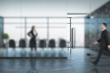 Obraz premium Businessman walking in conference interior hall with blurred glass wall.