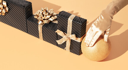 Gift box polka dot design in isometric on trendy golden beige background. Present, Holiday Christmas concept. Stylish minimal still life scene hand in golden gloves