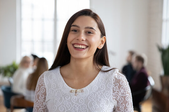 Close up profile picture of smiling millennial woman worker laugh feel optimistic motivated at workplace. Headshot portrait of happy young female employee satisfied with good work atmosphere.