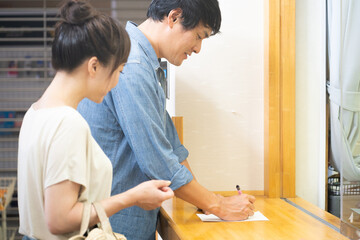 受付で何か書き込む男女
