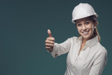 Woman wearing a safety helmet and giving a thumbs up