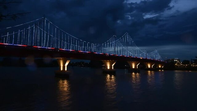 The scenery of the Tapi river bridge with the colorful light decoration at dusk in Surat Thani province, Thailand.