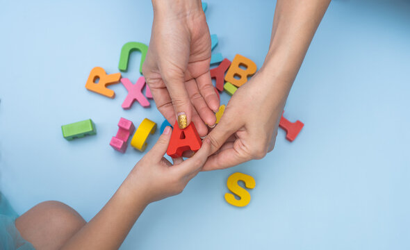 Close up hands of mother and daughter studying the alphabet