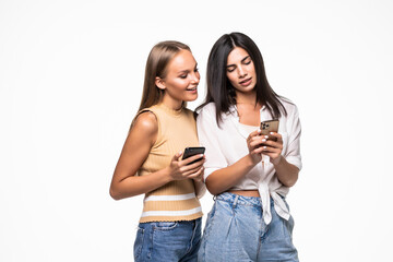 Fototapeta premium Two smiling women friends using mobile phone isolated on white background