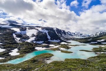 Scenic Gamle Styrnefjellsvegen with turquoise lake and snowcapped Mountains, Grotli, Norway