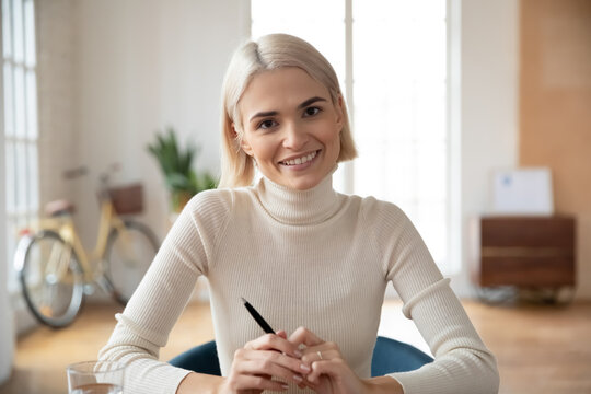 Headshot portrait of smiling young Caucasian woman talk on video call at office workplace. Happy motivated female employee or worker have webcam virtual interview or conference. Employment concept.