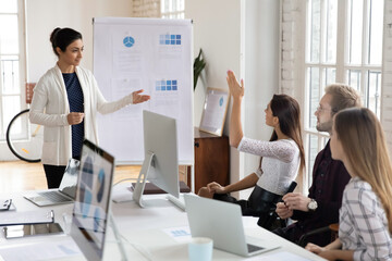 Confident millennial female indian trainer interact with employee asking answering question at office meeting. Young ethnic coach talk with motivated worker raise hand at briefing. Feedback concept.