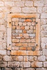 Old brick wall with a window in the center of the frame, bricked.