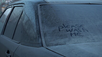 On a dirty car is written: "Please wash me." Prank over the owner of a black car.