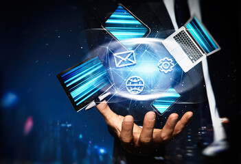 Young businessman holding different devices and digital icons in hand on blue background, closeup
