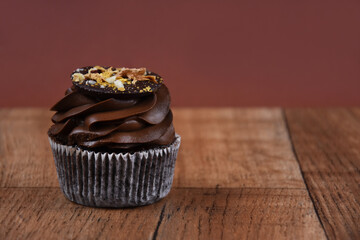 Chocolate cream cupcake on a wooden background stock images. Chocolate cupcake on the table. One delicious cupcake brown frame stock images. Chocolate cupcake brown border with copy space for text