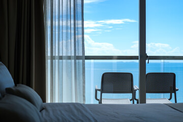 View from the bed through the window saw two chairs on the balcony, the background is sea and sky.