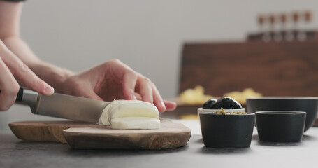Obraz na płótnie Canvas man hands cutting mozzarella cheese on the wooden cutting board