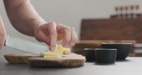 Obraz na płótnie Canvas man cutting hard cheese with knife on wood board