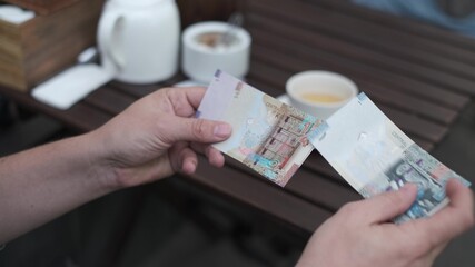 Man counts Kuwaiti dinars to pay for coffee in a street cafe