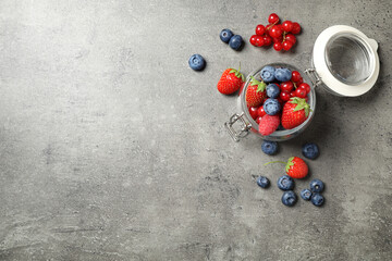 Mix of ripe berries on grey table, flat lay. Space for text