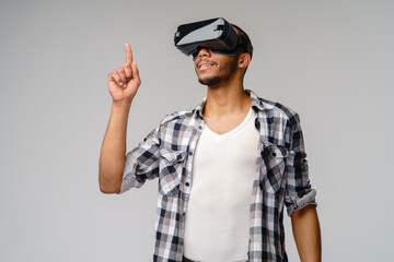 Young African-American young man wearing vr virtual reality headset over light grey background