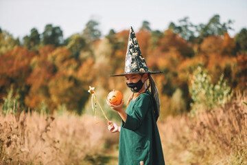 Halloween kids. Cute girl in a hat holding a pumpkin.