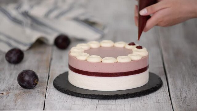 Pastry chef decorated a delicious plum mousse cake with jam.