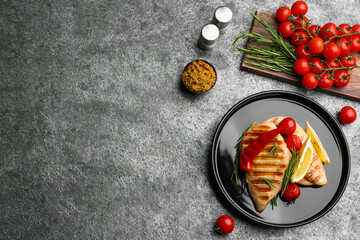 Flat lay composition with tasty grilled chicken fillets on grey table. Space for text