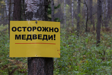 A sign with the inscription "Caution bears" in Russian in the forest