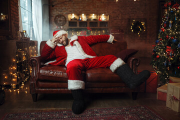 Obraz premium Bad Santa claus with hangover sitting on couch