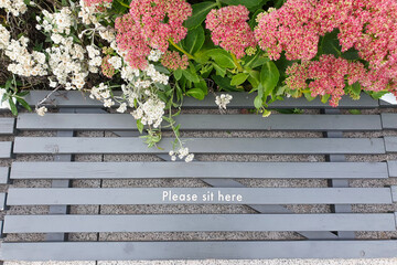 Top view of a park bench with an inscription. Please sit here. Social distance.
