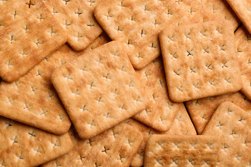 Many delicious crackers as background, top view