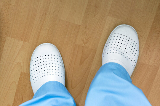 White Medical Footwear Of The Doctor On The Legs, Top View.