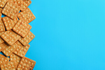 Delicious crackers on light blue background, flat lay. Space for text
