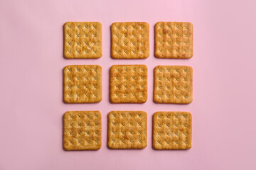 Delicious crackers on pink background, flat lay