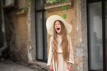 Girl with long hair on a city street. The girl screams. Anger and scream
