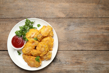 Tasty deep fried chicken pieces served on wooden table, top view. Space for text