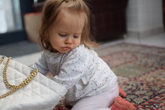 M&auml;dchen/Kleinkind kramt heimlich in der Handtasche der Mutter.