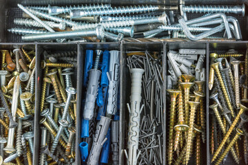 A box with a variety of screws, nails, drills, dowels as background, texture, pattern.