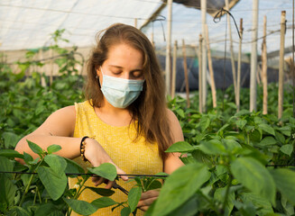 woman in a greenhouse with mask