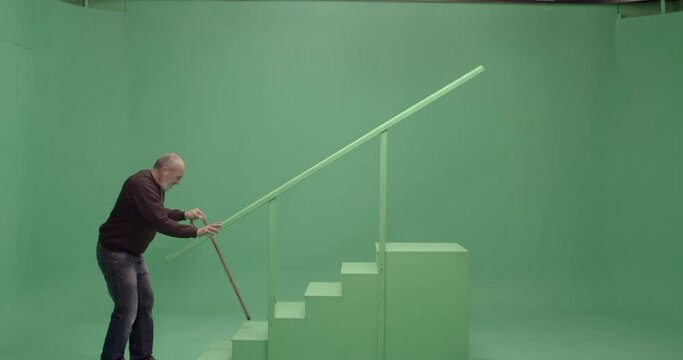 Studio, Slow Motion, Green Screen, A Senior Man With A Walking Cane On A Green Staircase, London, UK