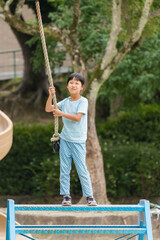 真夏の公園でターザンロープを遊んでいる可愛い子供