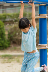 Obraz premium 真夏の公園で雲梯遊具を遊んでいる可愛い子供