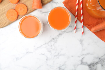 Freshly made carrot juice on white marble table, flat lay. Space for text