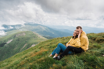 Naklejka na ściany i meble Happy couple in love sit on the top of a mountain and sensual hugging enjoying with a scenic nature views around them