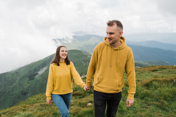 Fototapeta na wymiar A loving happy caucasian couple walking around the mountains holding hands and enjoying of a beautiful landscape
